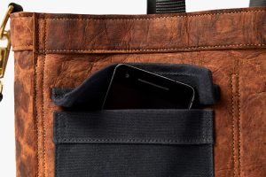 Detail of the Driver bag made from mycelium leather in Mylo™ Unleather developed by Bolt Threads and designed by Chester Wallace. Image shows texture and softness of the material with contrasting buckskin-style Unleather with black detailing.